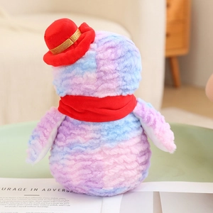 Christmas penguin plush toy in tie-dye colors with red hat and scarf in a cozy room