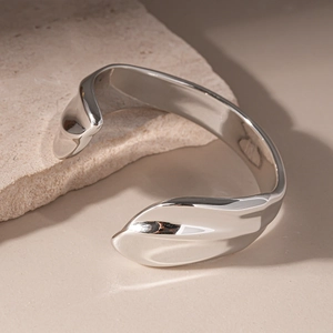 Detailed view of irregular silver cuff bracelet with organic waves on natural stone