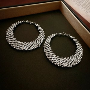 Macro shot of silver woven mesh hoop earrings with sparkling rhinestones in a gift box