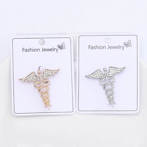Detail view of gold and silver Caduceus brooches with wings inlaid with clear rhinestones
