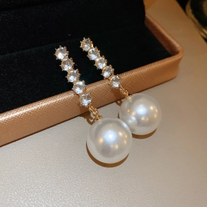 Macro shot of long drop earrings with shiny white pearls and vertical rhinestones