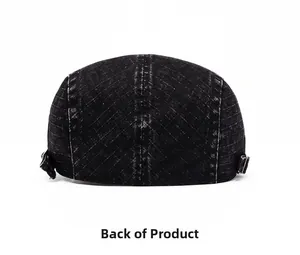 Detail of washed black denim flat cap showing metal side buckles and white contrast stitching