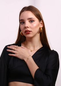 Golden flower jewelry set with necklace, earrings and bracelet worn by model on grey background
