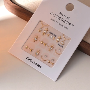 Detailed view of 3D gold bow nail art stickers with crystal rhinestones and chain elements