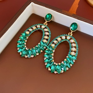 Macro shot of French vintage gold earrings with green crystals and sparkling rhinestones