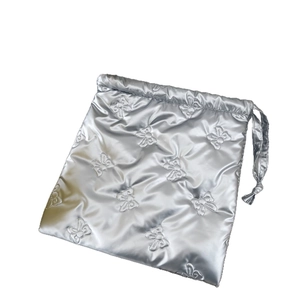 Silver metallic drawstring bag with quilted bow pattern for cosmetic storage