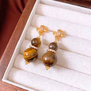 Close-up of vintage tiger eye gourd earrings with zircon accents in a wooden jewelry box