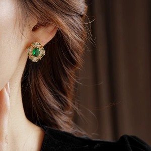 Détail de boucles d'oreilles dorées vintage avec pierre verte et halo de zircon