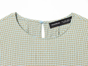 Detail der blau-gelb karierten Bluse mit Knopfverschluss hinten und dem Markenetikett