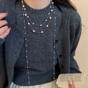 Detail einer mehrlagigen Perlenkette mit Silberkette an Model im grauen Cardigan