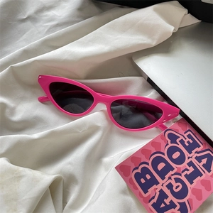 Fashionable bright pink thick frame cat-eye sunglasses with dark lenses on white fabric