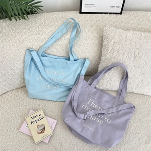 Detail of light blue and lavender canvas tote bags with dream lettering and shoulder straps