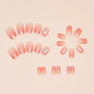 Détail de faux ongles dégradés roses avec motifs papillon et strass brillants décoratifs