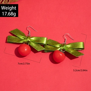 Détails des boucles d'oreilles de Noël avec nœud vert et perle rouge en gros plan