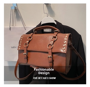 Close-up of caramel brown PU leather satchel with gold studs and buckle details