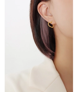 Detail showing irregular heart stud earring with beaded gold texture on female model