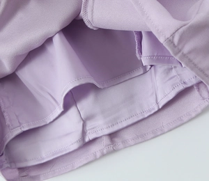 Détail de la doublure intérieure d'une robe lilas montrant le tissu et la couture précise