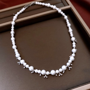 Close-up of elegant pearl necklace with star charms on a vintage leather jewelry tray