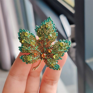 Macro shot of maple leaf brooch featuring green and yellow gradient crystals in alloy