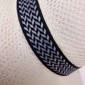 Close-up of fine woven straw hat texture with black and white geometric pattern band