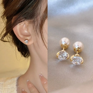 Macro shot of cubic zirconia and pearl double-sided stud earrings on satin