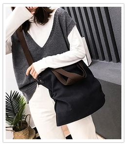 Vue lifestyle d'un grand sac fourre-tout en toile noire porté par un mannequin chic