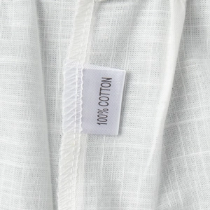 Detailed close-up of 100% cotton fabric texture and sewn material label on the white dress