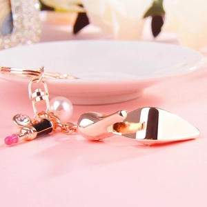 Detailed view of rose gold high heel and lipstick keychain with pearl and crystals