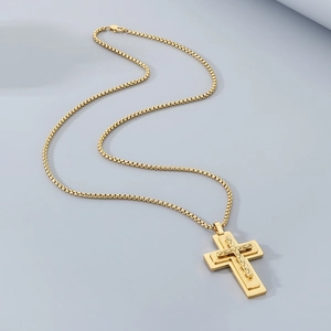 Macro detail of a layered gold cross pendant with twisted texture and box chain