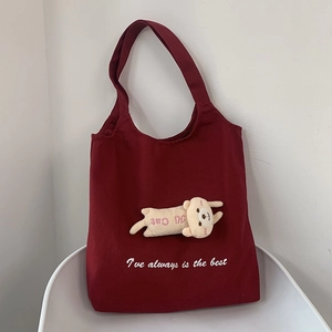 Detail of red canvas tote bag with a cute plush cat doll on a white chair