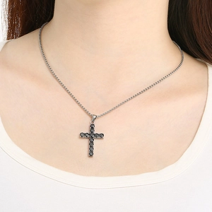 Silver chain necklace featuring a black crystal cross pendant worn by a model