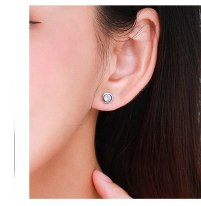 Close-up of minimalist S925 sterling silver round stud earrings worn on ear