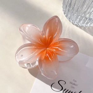 Détail d'une pince à cheveux en forme de frangipanier avec dégradé orange et blanc