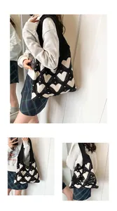 Detail showing the knitted texture and white heart pattern of the black tote bag