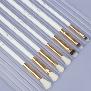 Close-up of seven professional soft eye makeup brushes with white handles and gold ferrules