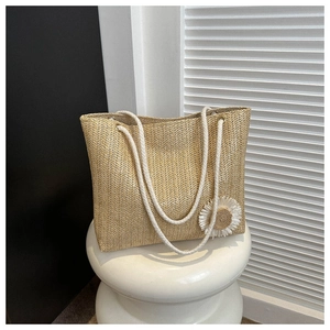 Detail view of straw woven tote bag featuring a white daisy flower and cotton rope handle