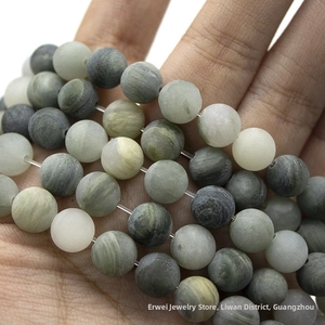 Macro detail of natural green grass stone beads with marble textures held in hand