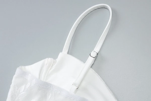 Detail of adjustable thin straps and intricate lace patterns on a white bodycon dress