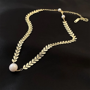 Golden leaf necklace with large pearl pendant and adjustable chain on black fabric