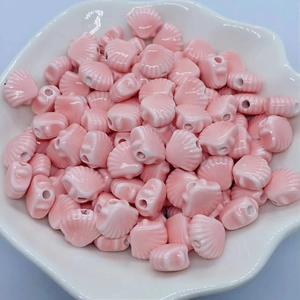 Macro shot of glossy pink shell-shaped ceramic beads with white texture in a wavy plate
