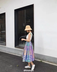 Detail of hand-woven raffia bucket hat with a summer plaid skirt and white tank top