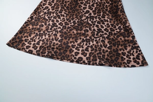Close-up detail of leopard print satin dress hem showing fine stitching and fabric texture