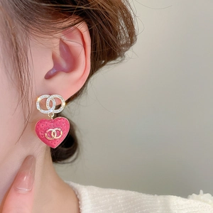 Detailed close-up of heart-shaped pink earrings with gold-plated finish and crystals