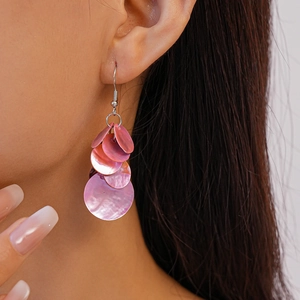 Gros plan sur les boucles d'oreilles pendantes en nacre rose portées par un mannequin