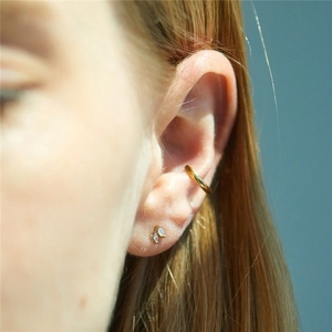 Close-up of gold marquise opal stud earrings and polished ear cuff on a model