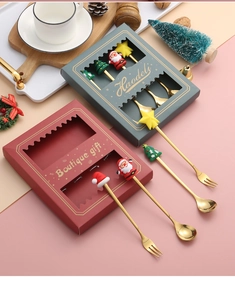 Close-up of golden Christmas spoons and forks set with festive silicone toppers in gift box