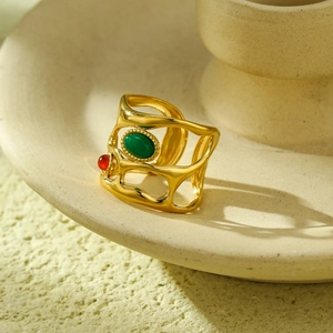 Luxury hollow gold ring featuring green oval and red round gemstones on ceramic plate