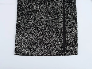 Detailed close-up of a black sequined dress featuring an elegant asymmetric high slit design