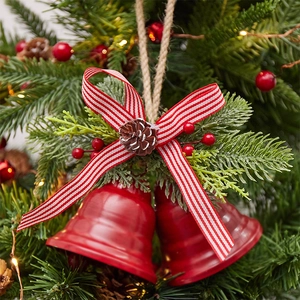 Rustic Christmas bells with red ribbon and pine cone decoration on a jute rope