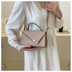 Beige crocodile texture crossbody bag styled with a white lace dress for a trendy look